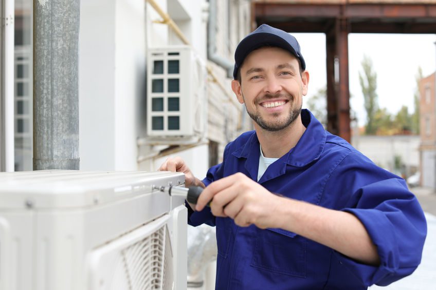 Male technician repairing air conditioner outdoors