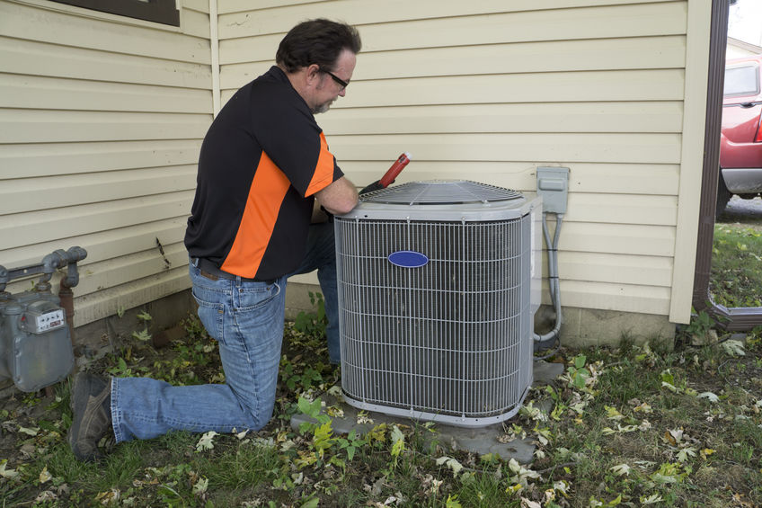 Repairman checking outside air conditioning unit for voltage.