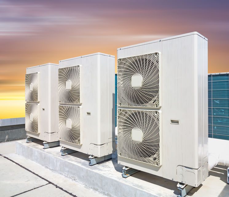 Air compressor on roof deck with sky background.