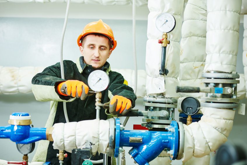 Engineer technician installing manometer, pipes and faucet valves of heating system in a boiler room